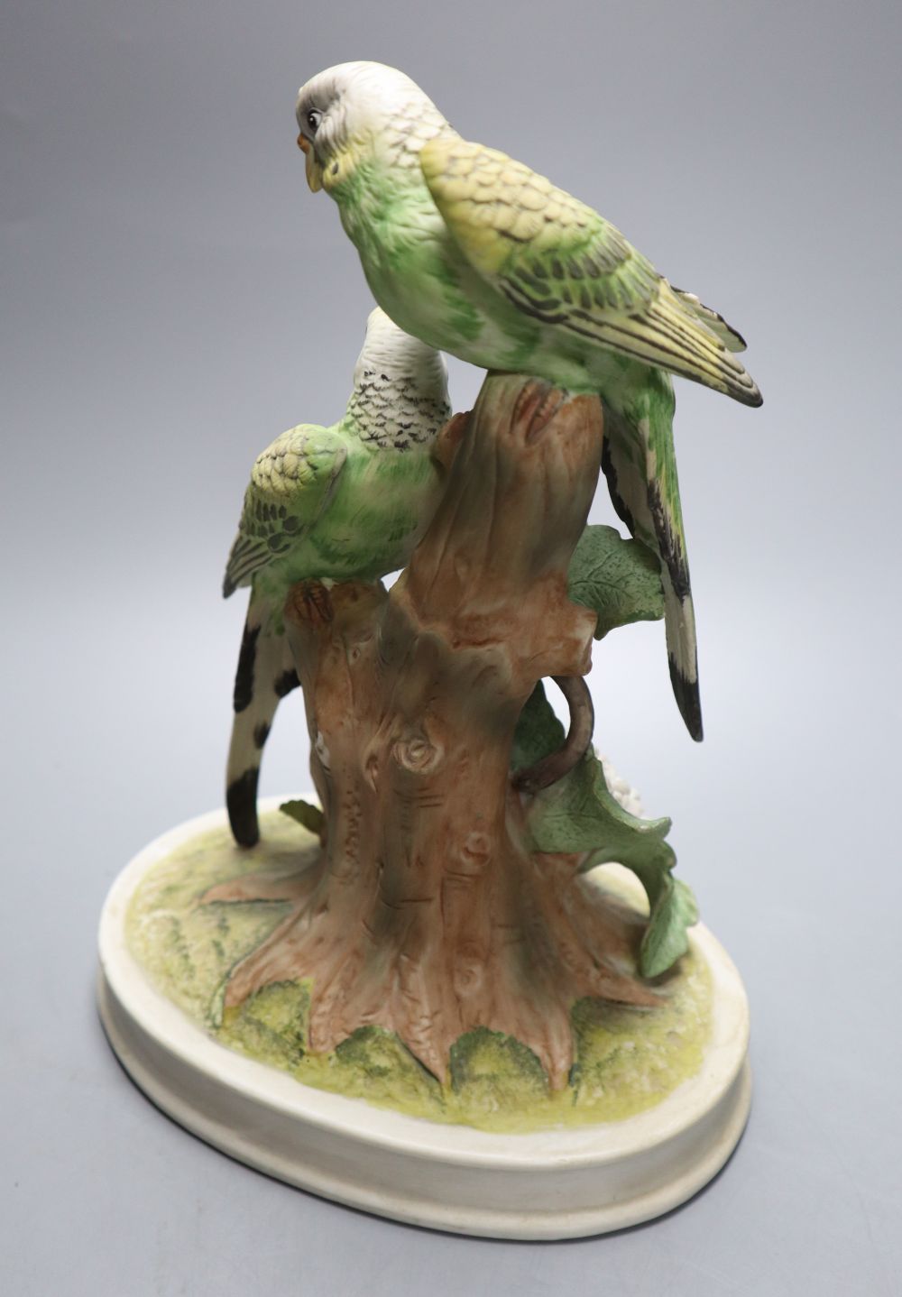A Continental tinted biscuit porcelain group of two budgerigars, 26cm high